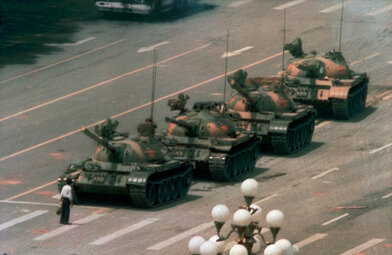 An image of a man standing in front of a line of tanks.