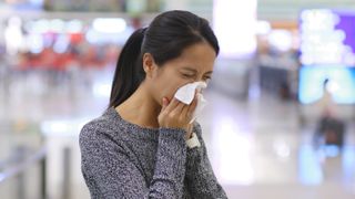 Woman sneezing at an airport, virus spread.