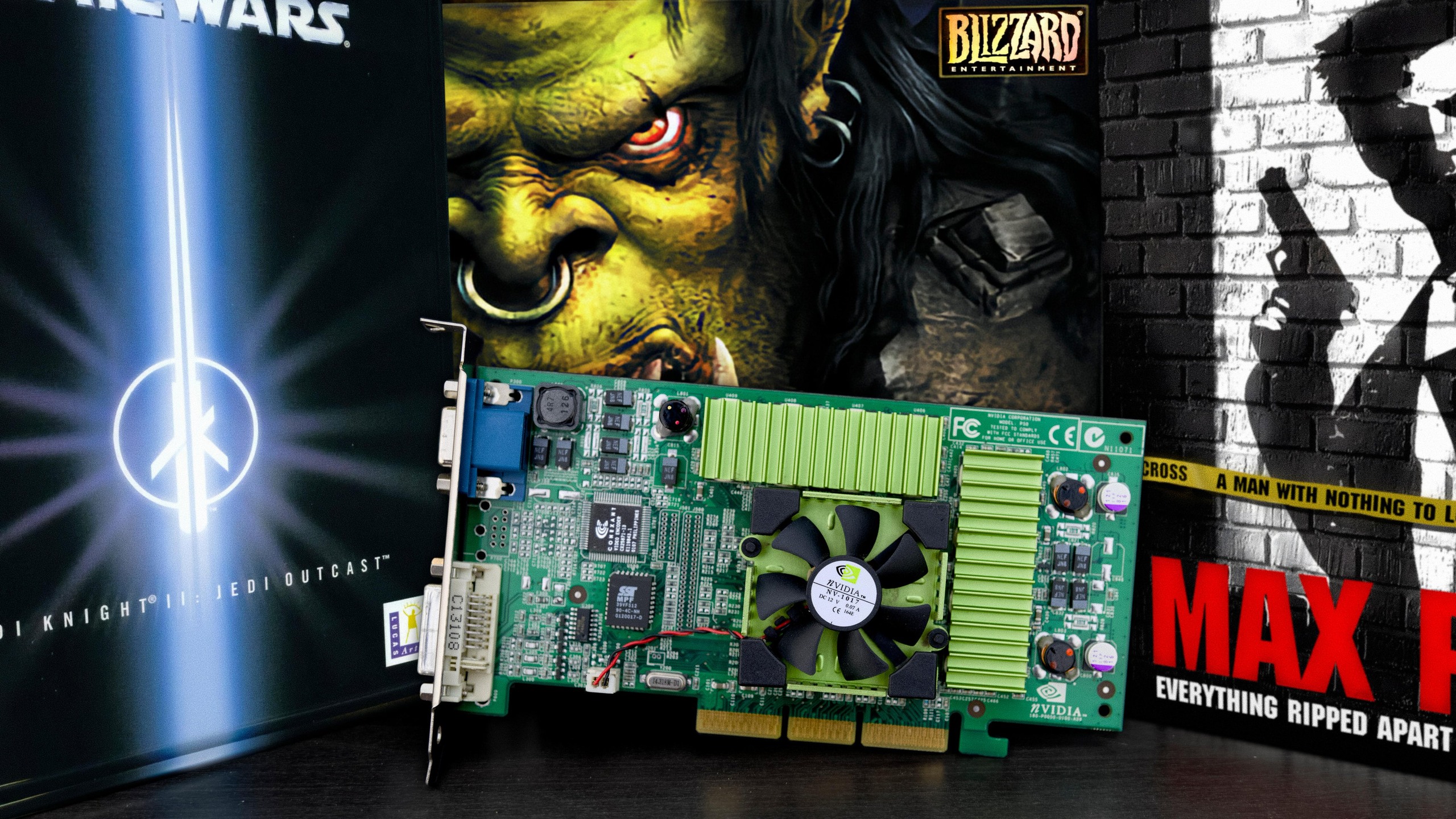 A GeForce 3 graphics card flanked by game boxes for Star Wars Jedi Knight 2, Warcraft III, and Max Payne.