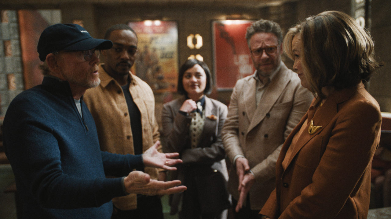 Ron Howard talks with Catherine O'Hara. while the rest of the room watches in The Studio S1 E3 - "The Note."