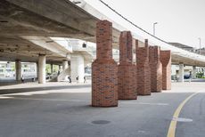an outdoor area with concrete road held up by concrete pillars, with red brick artistic pillars