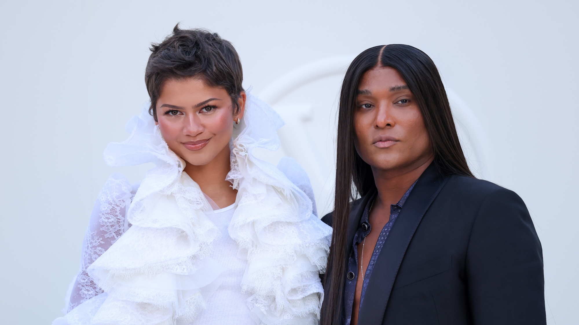 Zendaya with short hair and white frilly outfit posing next to Law Roach at Paris Fashion Week 2026