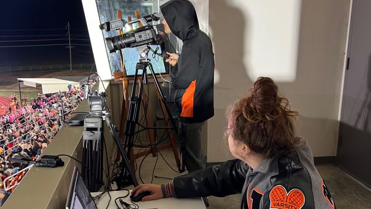 A camera man using JVC cameras at a high school football game. 