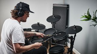 Man wearing a hat playing an electronic drum set