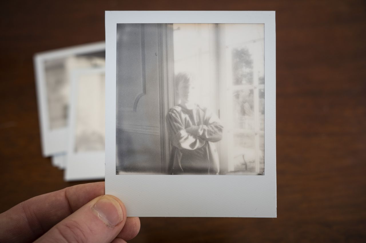 Polaroid SX70 instant print in the hand, black and white portrait
