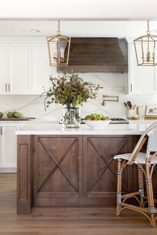 white kitchen with a wooden panelled ornate kitchen island and wooden bar stool