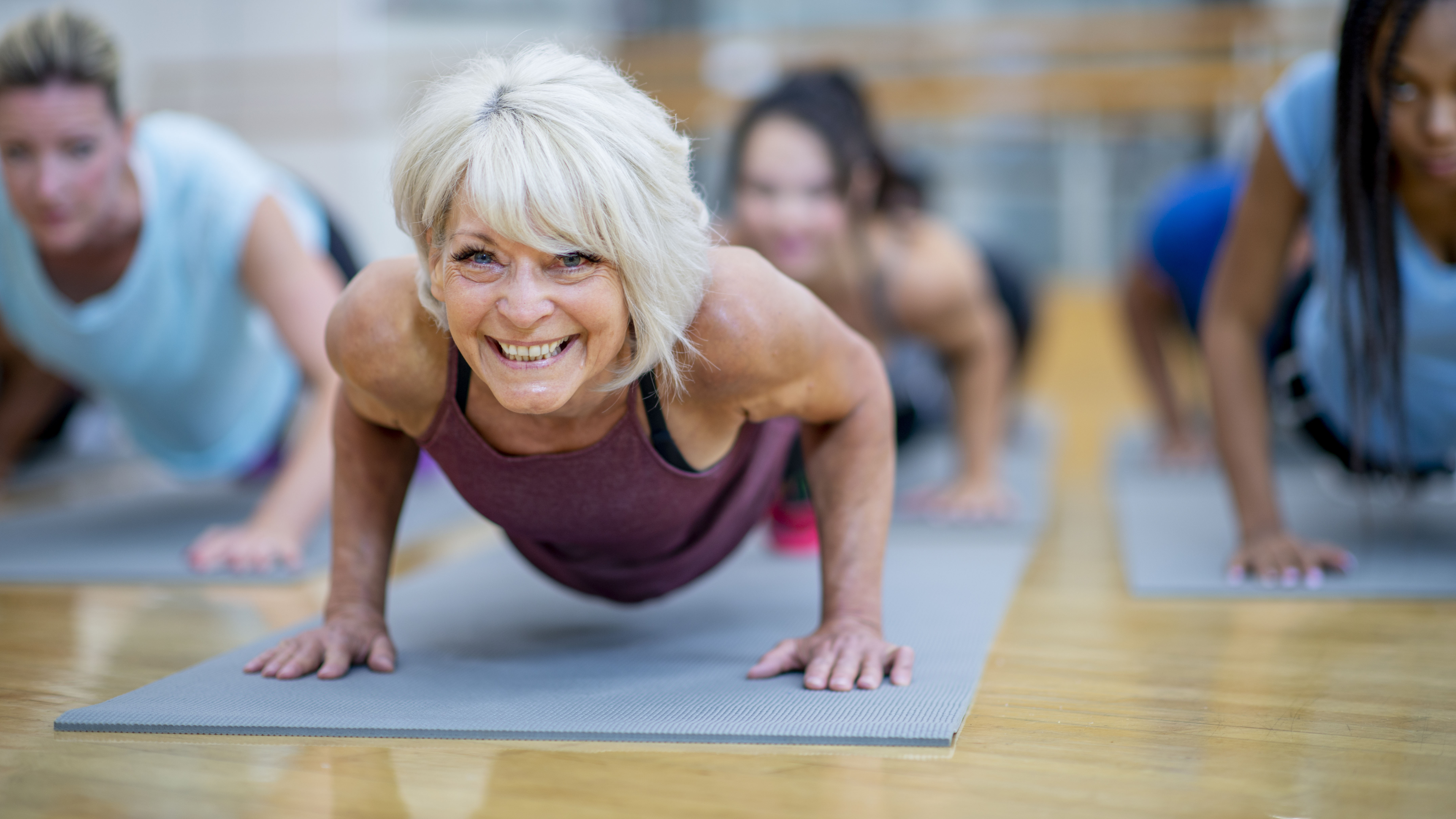 Senior woman doing plank in gym class