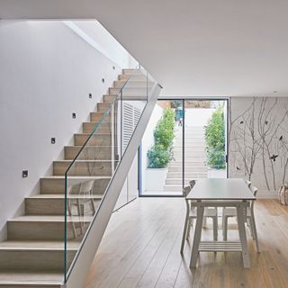 Open stair case with glass balustrade over looking dining table