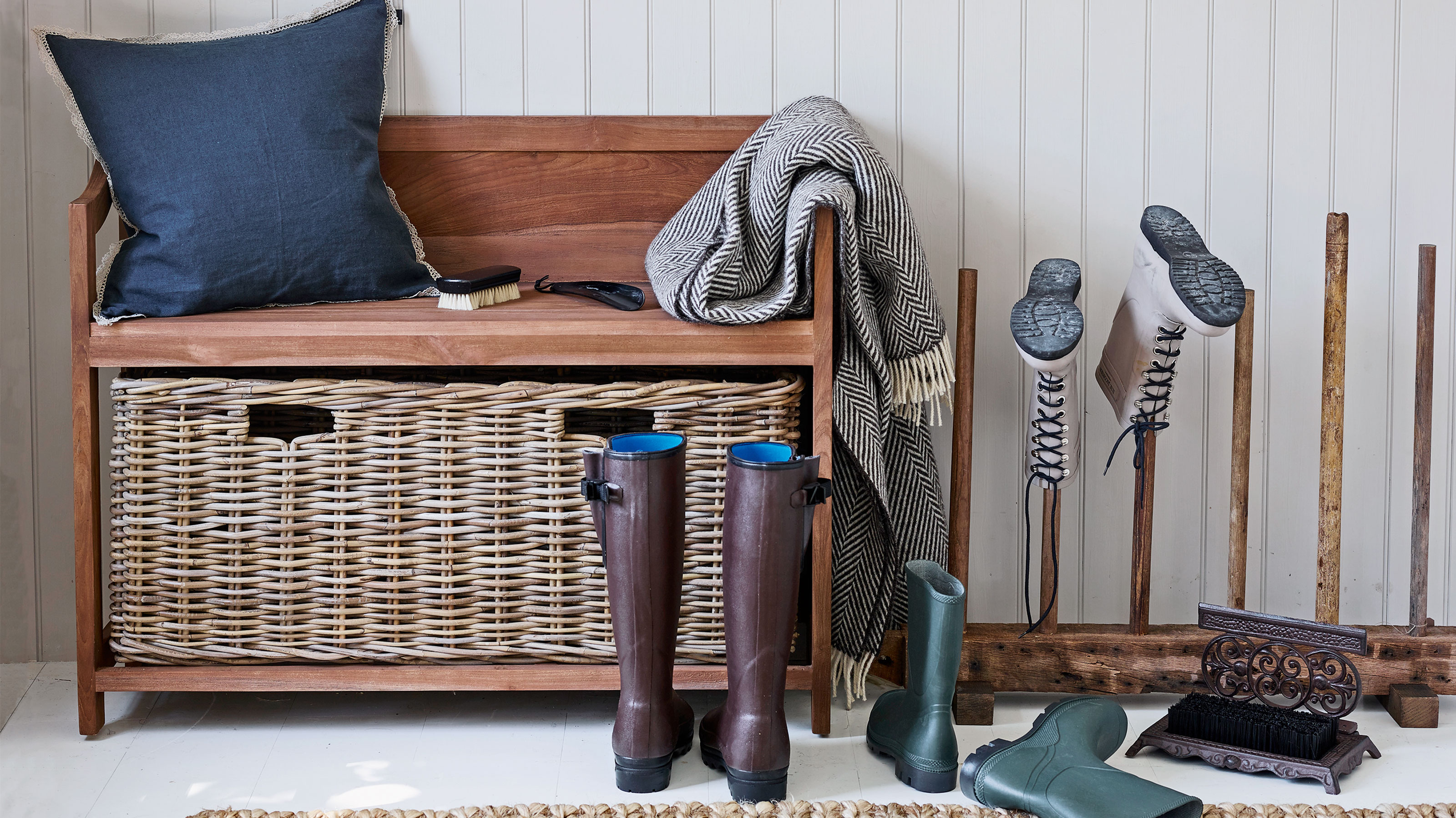 White hallway with rattan and wood bench and welly storage