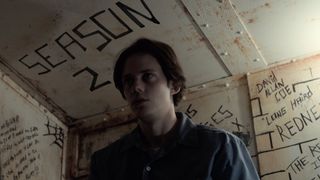 A still from the TV show castle rock in which a character stands in a room with writing scrawled on the walls
