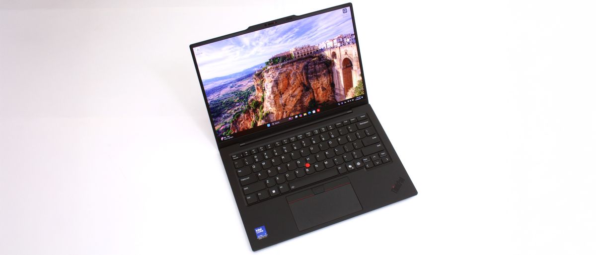 An open and powered on laptop against a white background, showing a structure built into the side of cliff on screen.