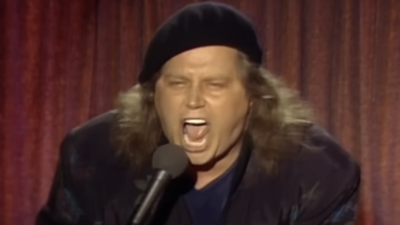 Sam Kinison screaming into the microphone on stage in Rodney Dangerfield's 1986 special, It's Not Easy Bein Me