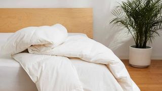 Brooklinen Down Comforter review: An image of the comforter thrown over the edge of a white bed