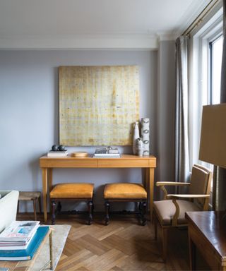 living room painted in farrow and ball's parma gray, a soft pale blue, with vintage pine furniture and a large abstract yellow painting