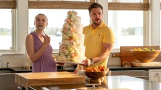 Thomas Winbury stands by a wedding cake with Abby Winbury in The Perfect Couple