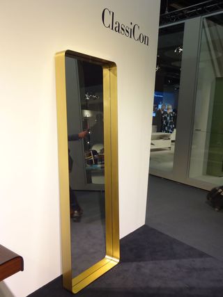 A brass-framed mirror standing against a wall