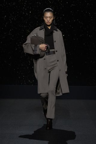 Hermès model wearing a gray long jacket with matching cigarette pants.