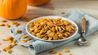 Roasted pumpkin seeds in a bowl on a towel