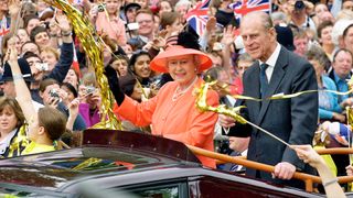 Queen Elizabeth II and Prince Phillip the Duke of Edinburgh ride along the Mall in an open top car