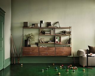 A walnut wood modular shelving unit with miniature cabinet in green living room