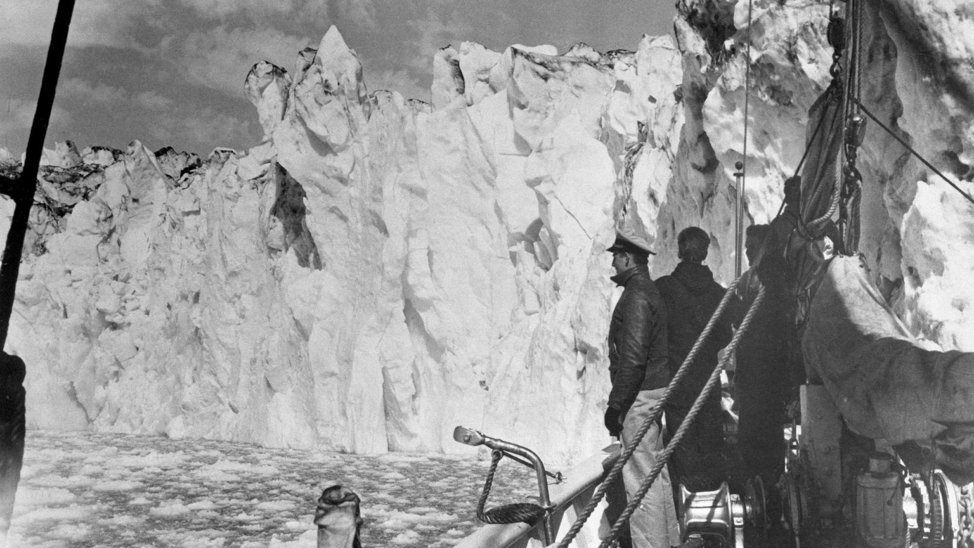 members of the US coast guard pictured on board a vessel next to an iceburg