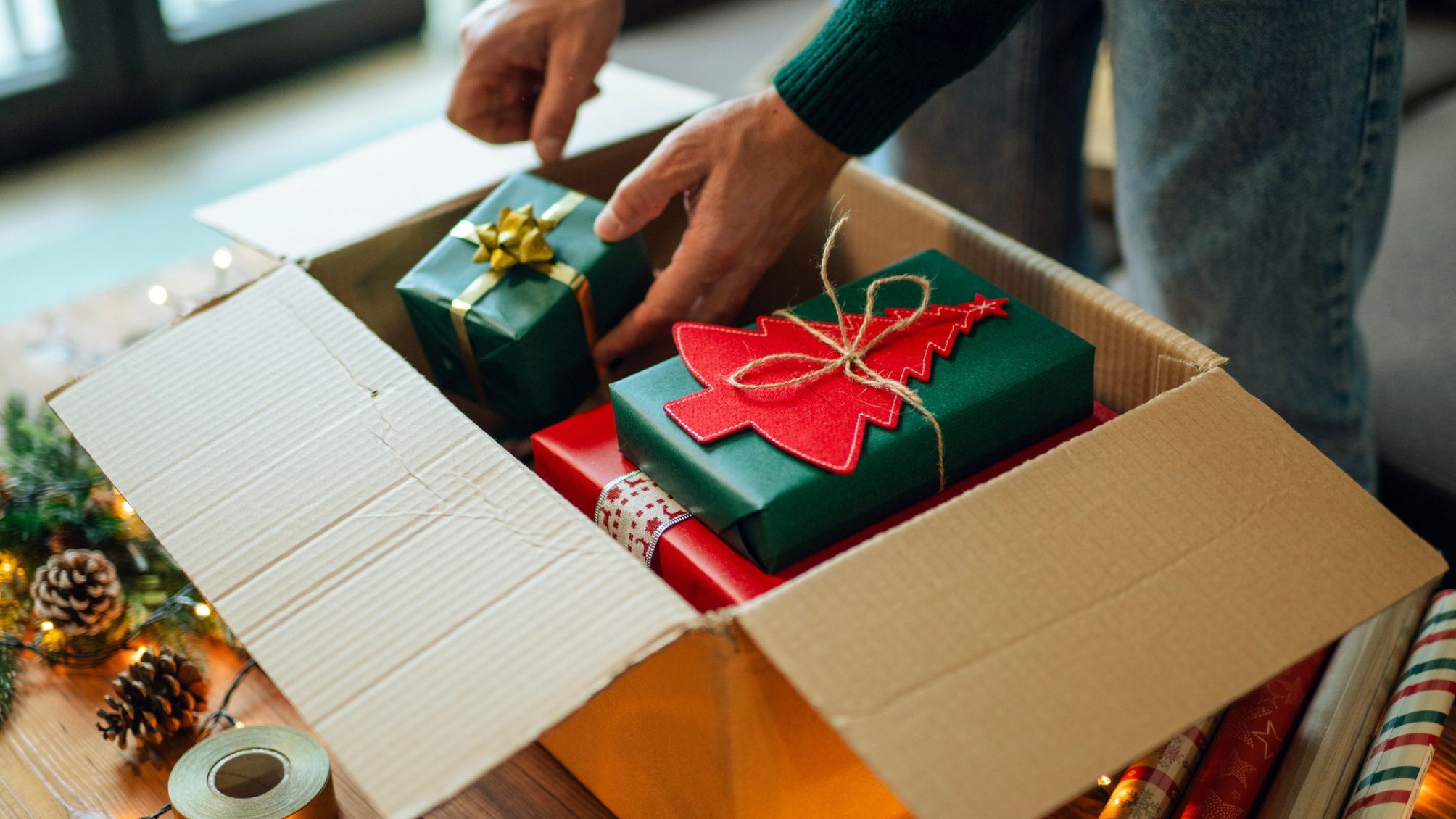 Man preparing Christmas gifts in a cardboard box for shipping. 