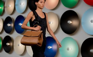 Black sleeveless dress model walking with bag in her hands
