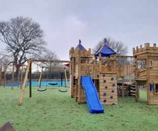 A toy castle and swings in a back garden