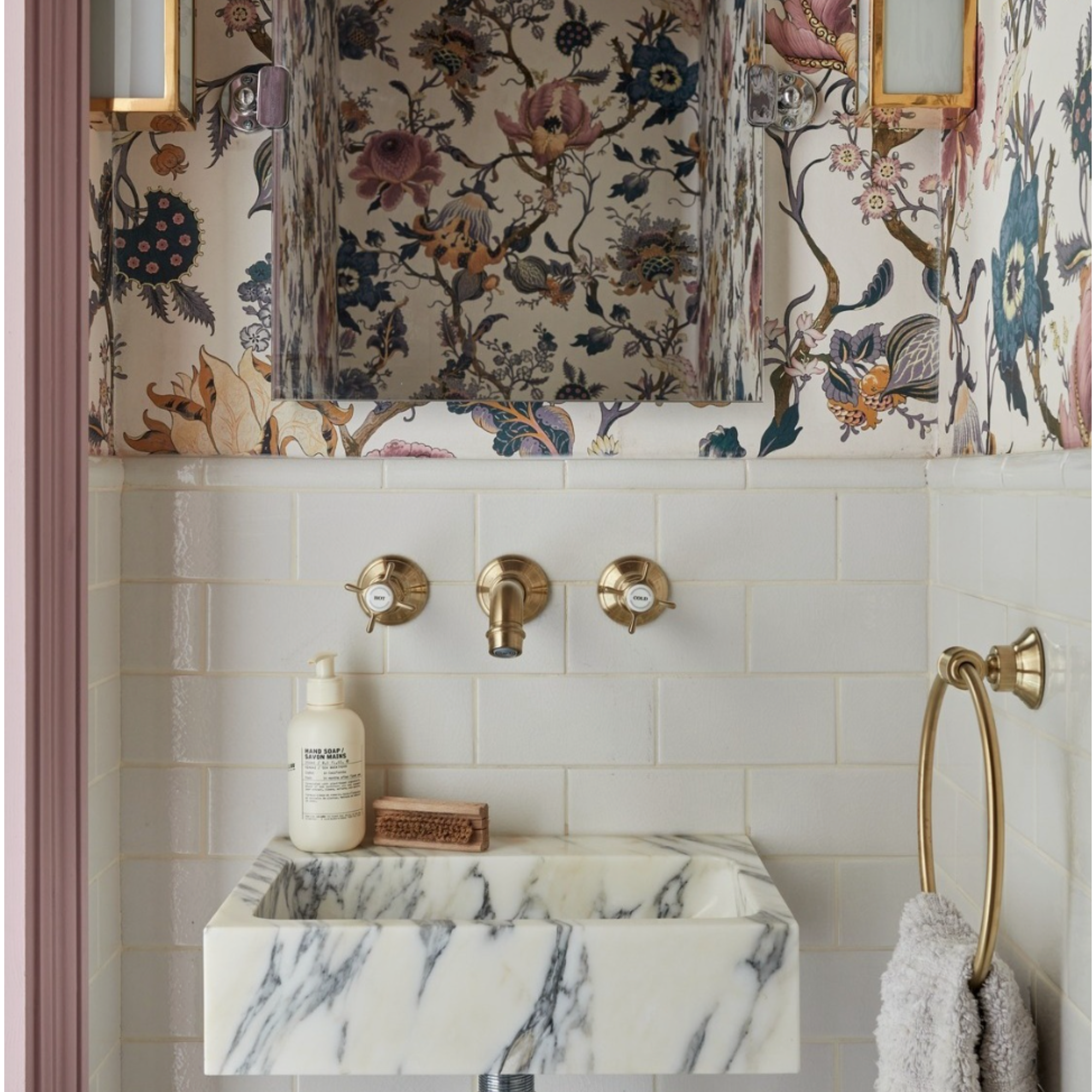 A marble bathroom basin with tile metro tiles behind and heritage wallpaper on walls