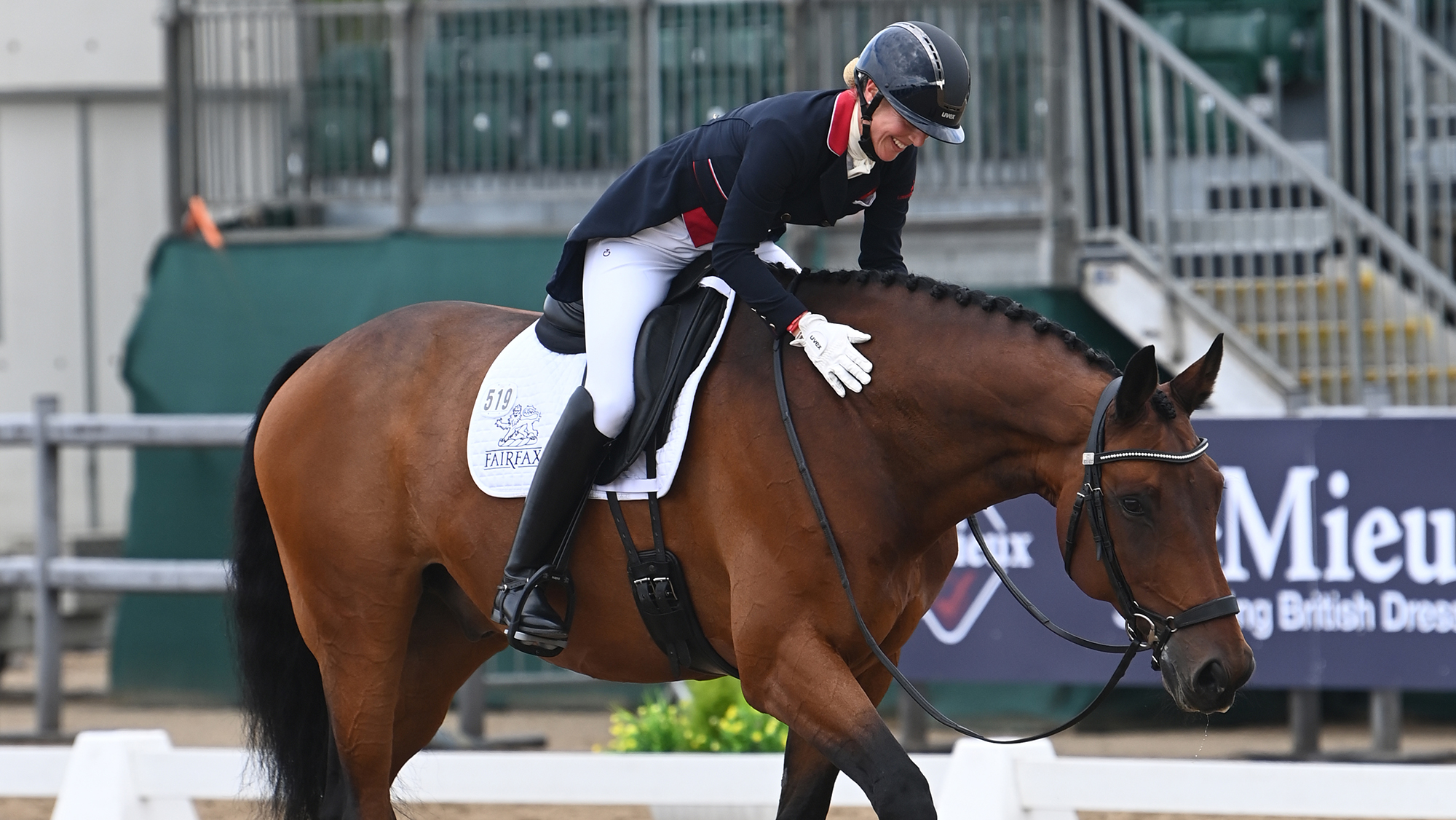 Top British dressage rider Laura Tomlinson stokes her bay horse Forrest Hill's neck as he walks on a free rein out of the dressage arena.