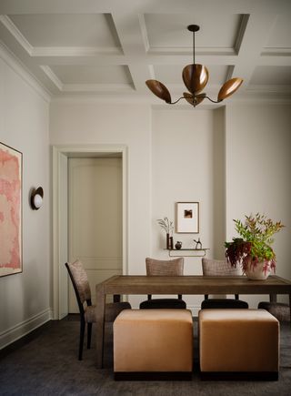 warm white dining room with copper lpendant light, art, and rust orange ottoman seats