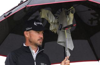 Brian Harman under his umbrella with a towel and gloves hanging from inside