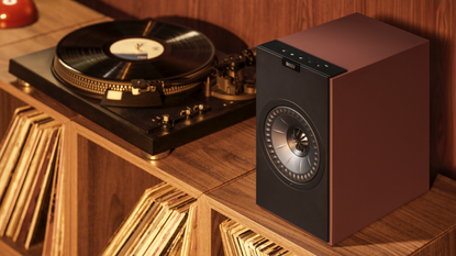 A KEF Coda W speaker beside a turntable on a wooden vinyl storage unit