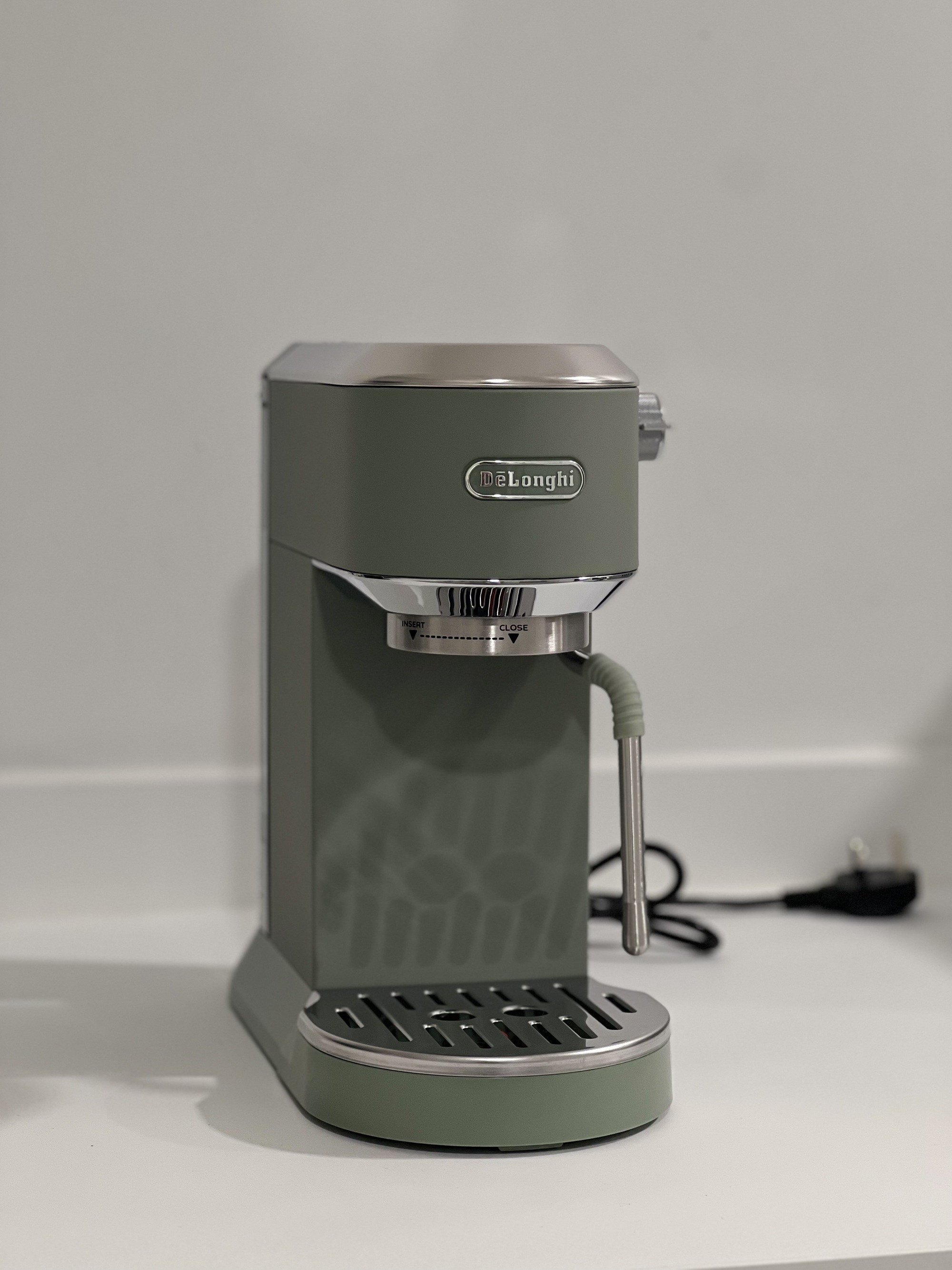 Image of the De'Longhi Dedica Duo machine in sage green, sitting on a white countertop.