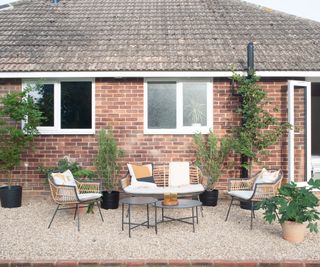 An patio outside the back of a bungalow with gravel and dining table and chairs