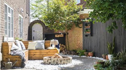 garden with dining table, wooden fencing, potted plants and fire pit 