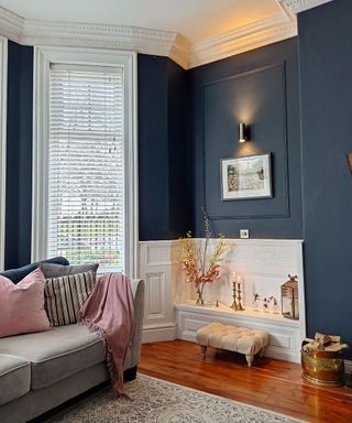 Corner of living room with pink armchair navy blue walls and part of a bay window