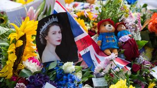 A portrait of Queen Elizabeth II is placed next to Union Jack flag and Paddington bears among flowers