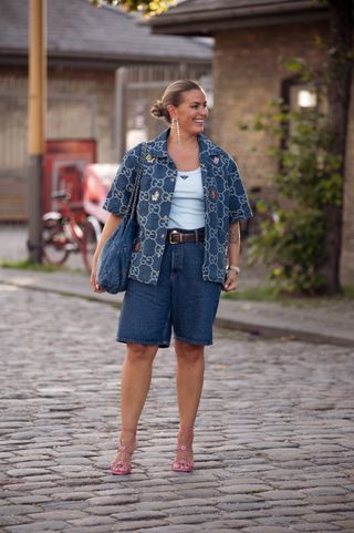 Janka Polliani wears blue shorts, light blue tank top, blue shirt outside Ganni during the Copenhagen Fashion Week Spring/Summer 2024 on August 10, 2023 in Copenhagen, Denmark.