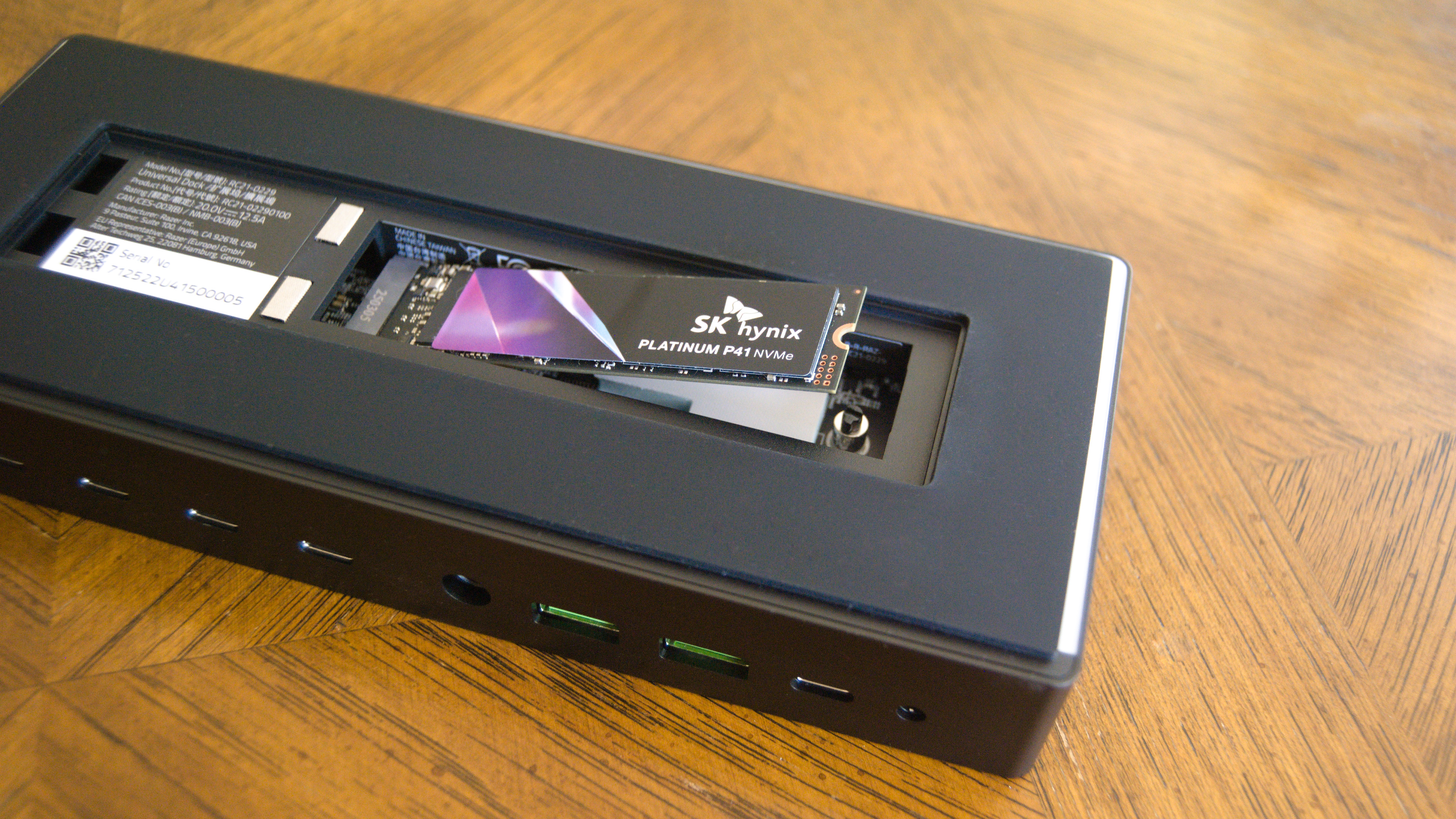 The Razer Thunderbolt 5 Dock Chroma sitting on a table with the SSD enclosure open and an SSD partially installed.