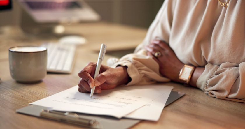 Businesswoman reading and signing a contract in a home office.