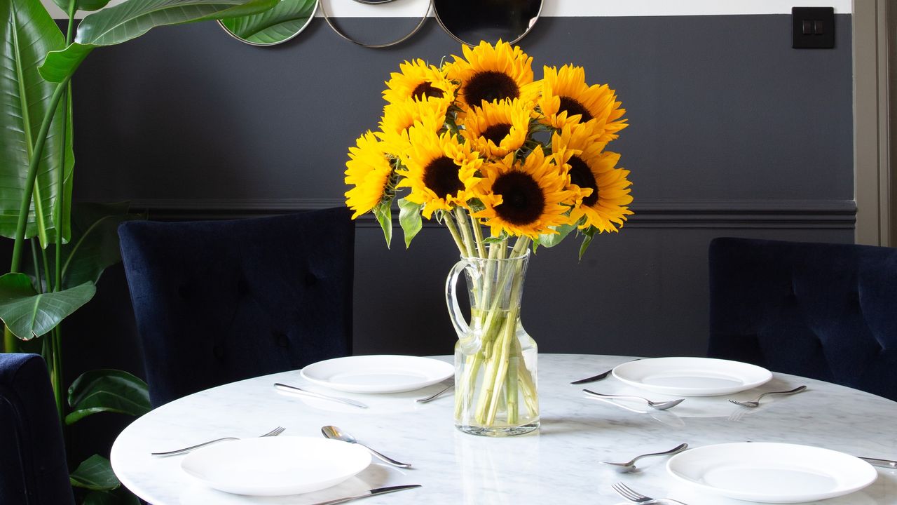 A vase of sunflowers on a set dining table