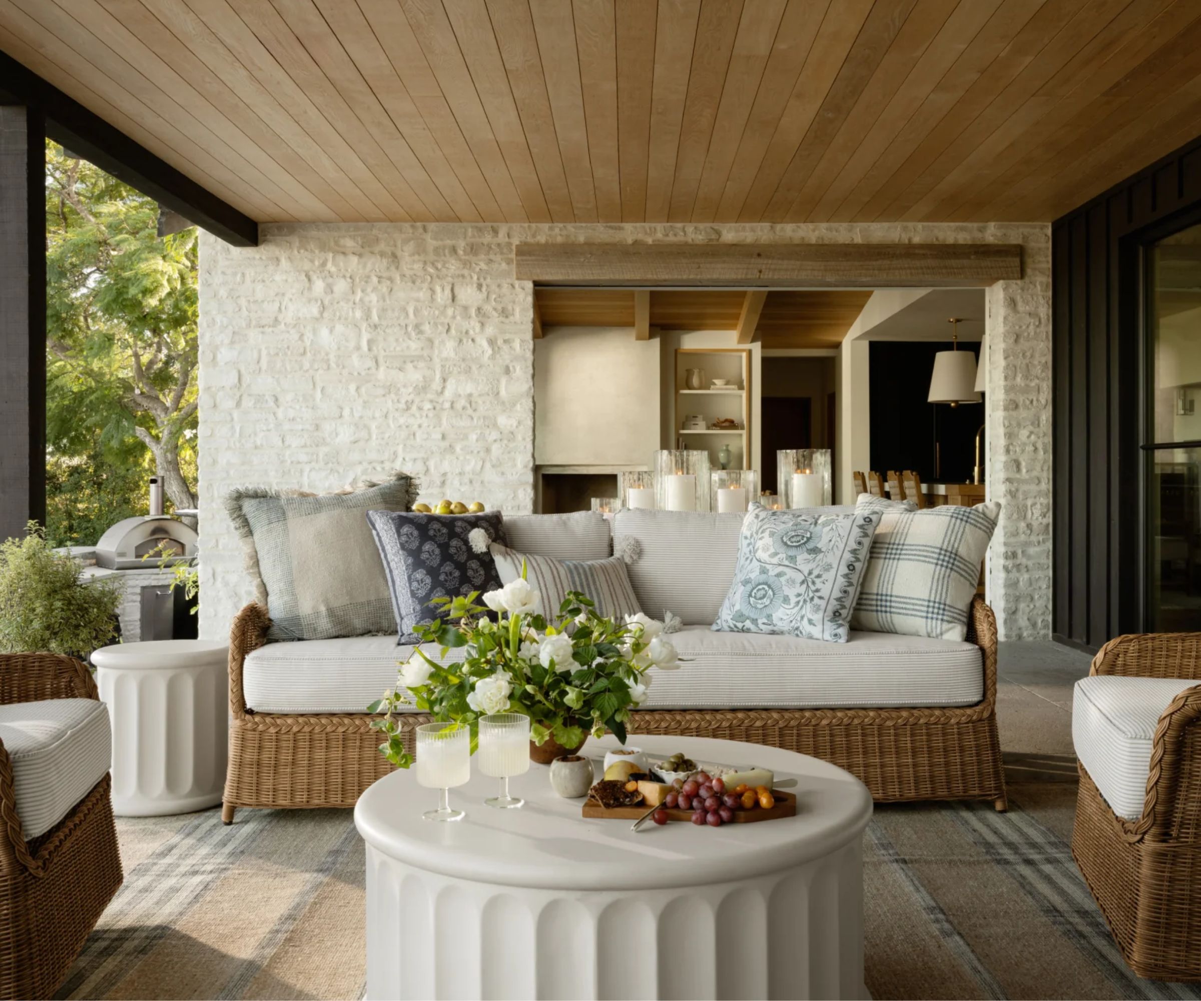 coastal farmhouse style outdoor living room area under a roof with wicker furniture and a white round coffee table