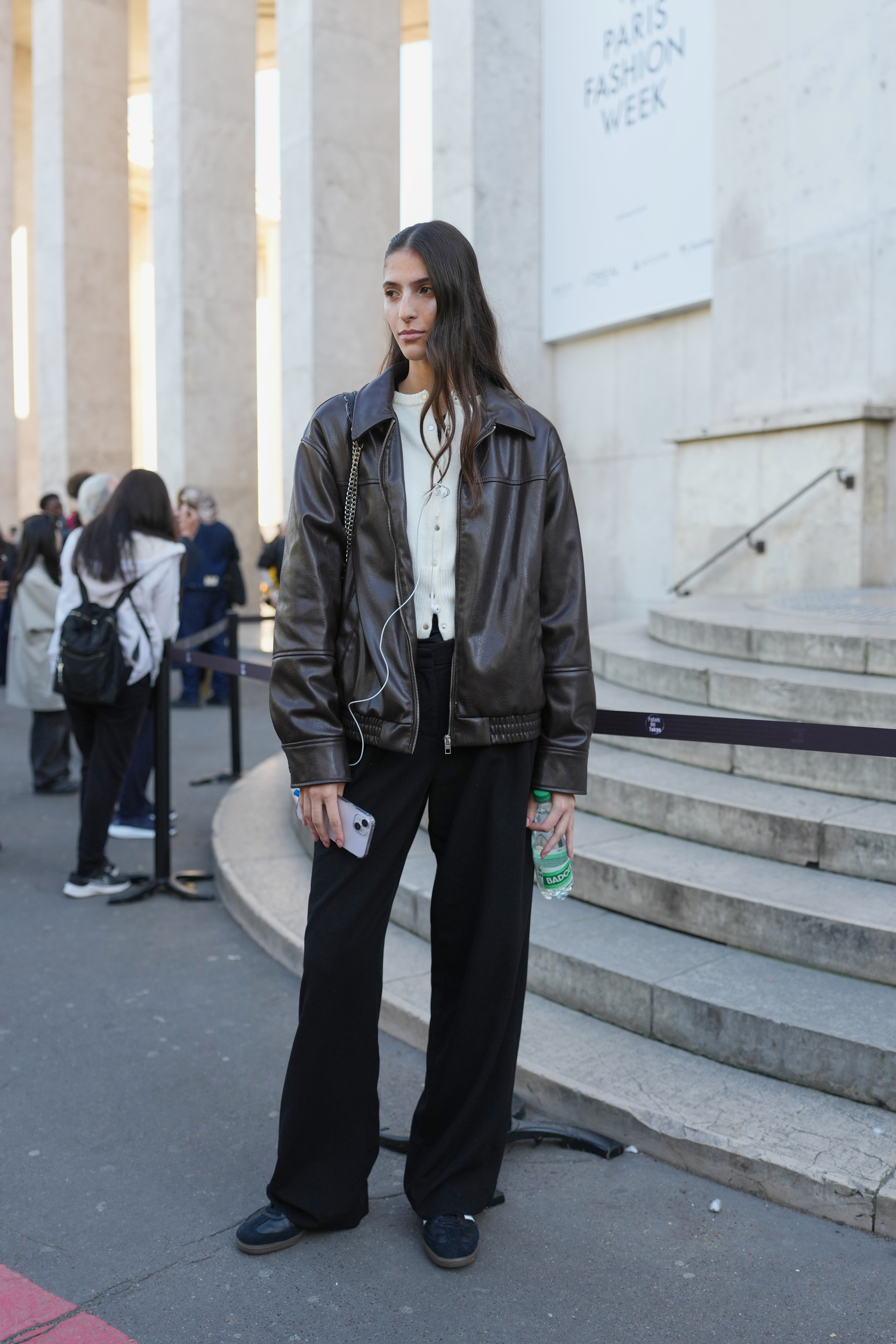 woman wearing leather jacket, cardigan, jeans, and sneakers