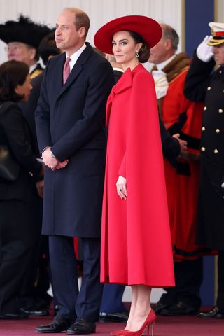 Kate Middleton wears a red cape and hat