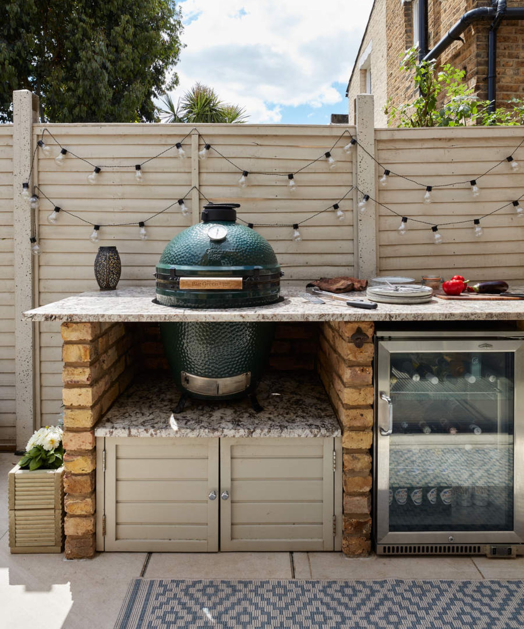 An outdoor kitchen with a big green egg barbecue grill and festoon lights