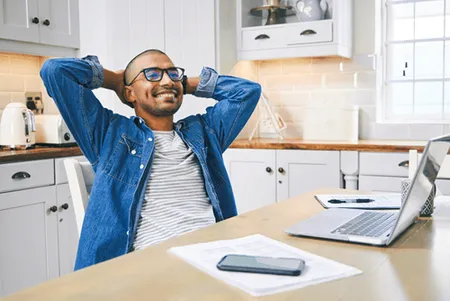 Man lying back on chair with laptop and phone on desk