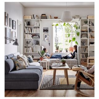 vertical storage space in a small living room, with a grey sofa and a window seat with children sat at it