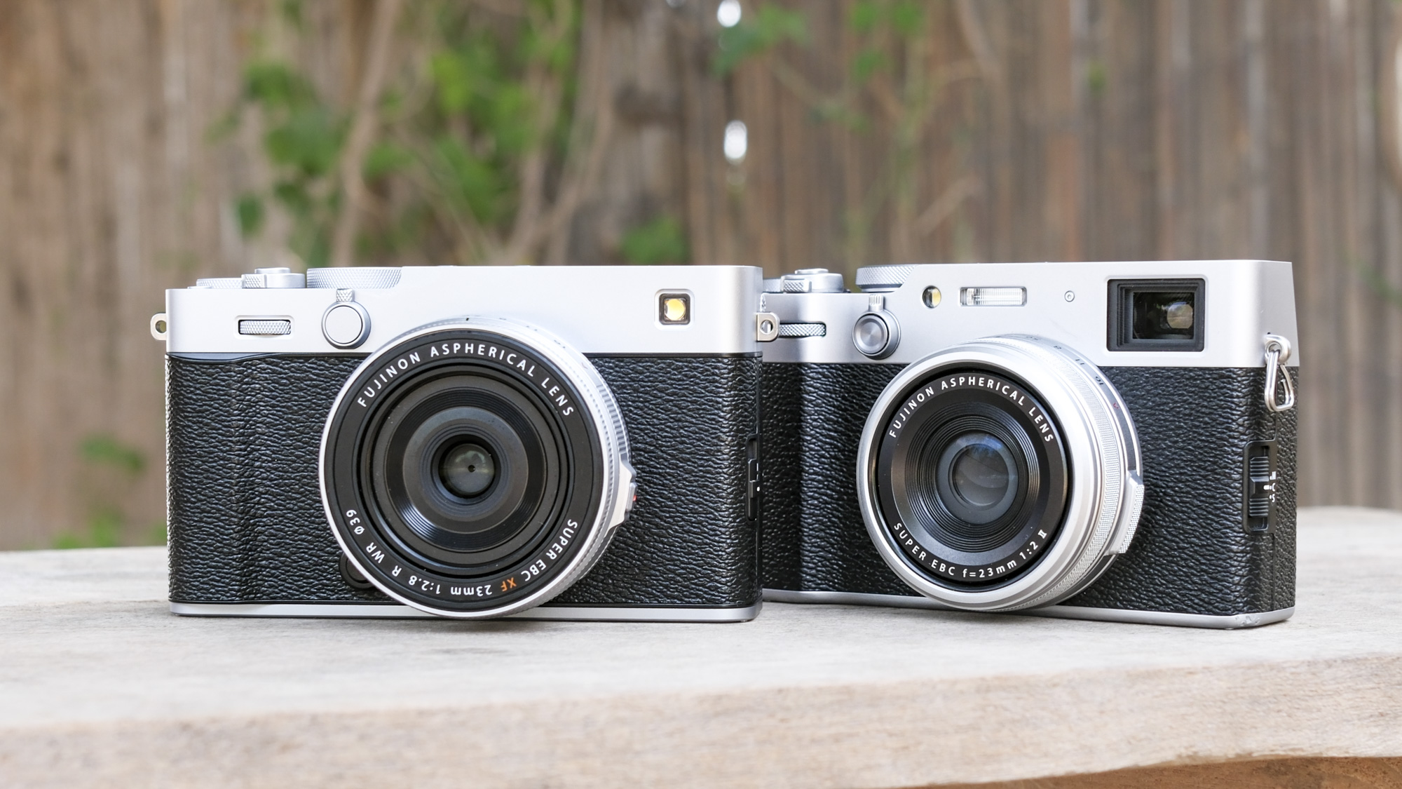 Silver Fujifilm X-E5 alongside the Fujifilm X100VI, on a wooden bench