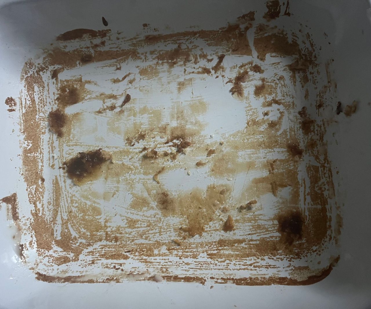 A white enamel dish with a red rim, with the remnants of cake mix around the base.